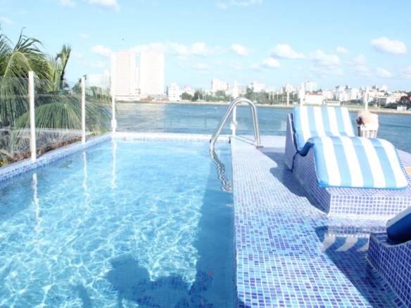 Mosaic pool of a luxury villa in Cuba, with the Vedado skyline across the water, Havana