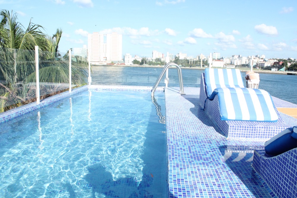 Mosaic pool of a luxury villa in Cuba, with the Vedado skyline across the water, Havana